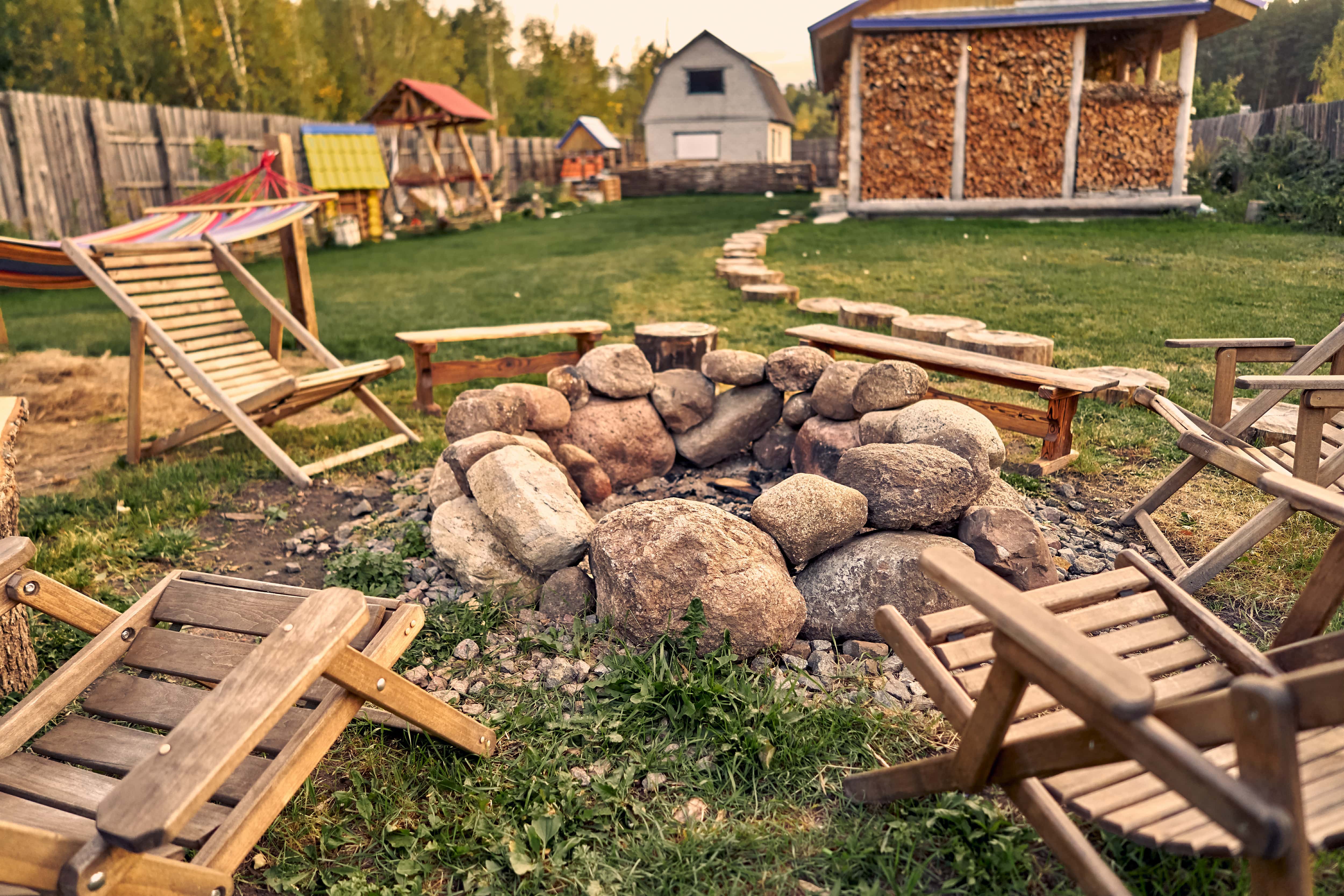 Stone fire pit and chairs in a backyard