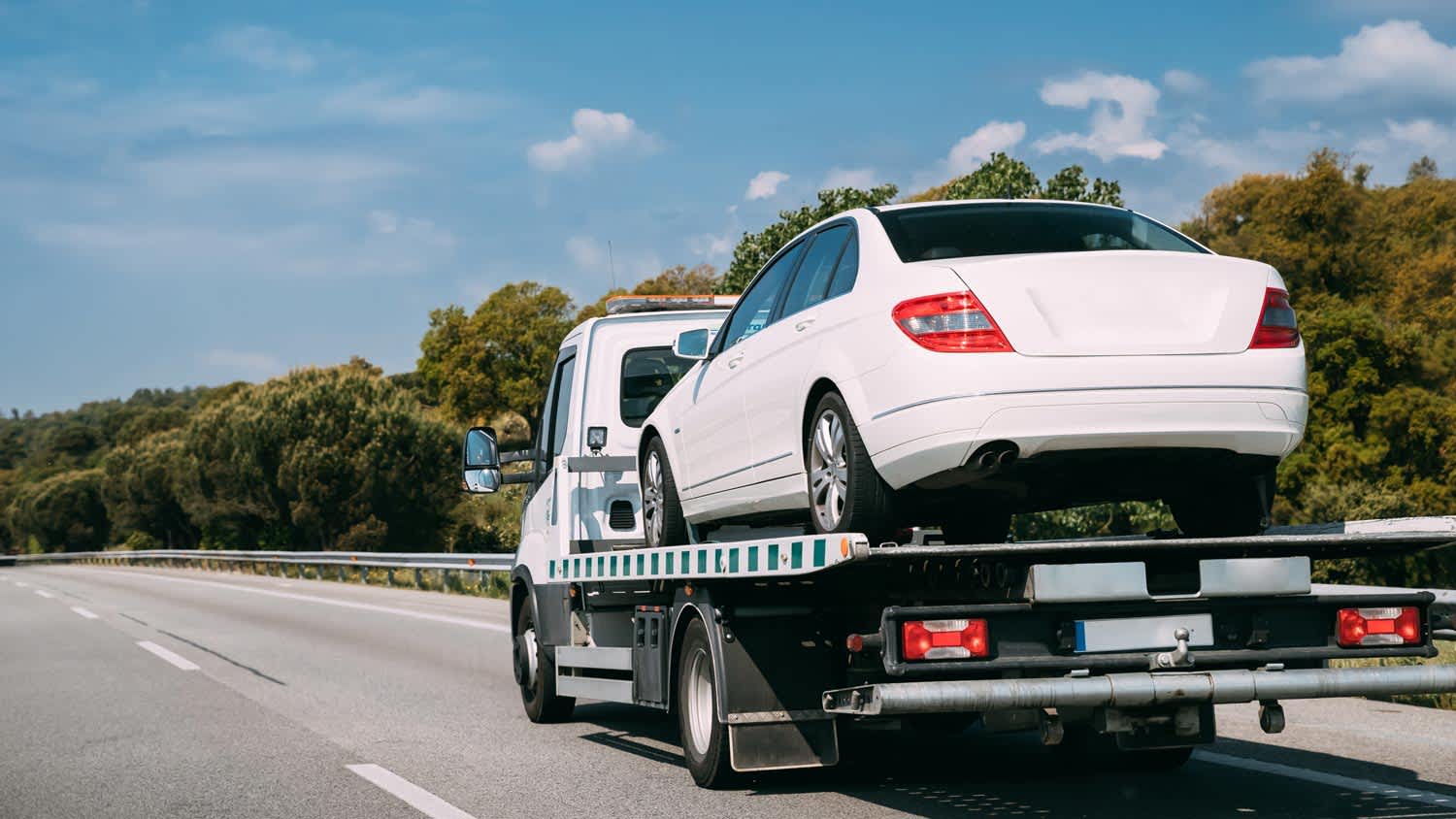 A tow truck on the freeway transporting a car