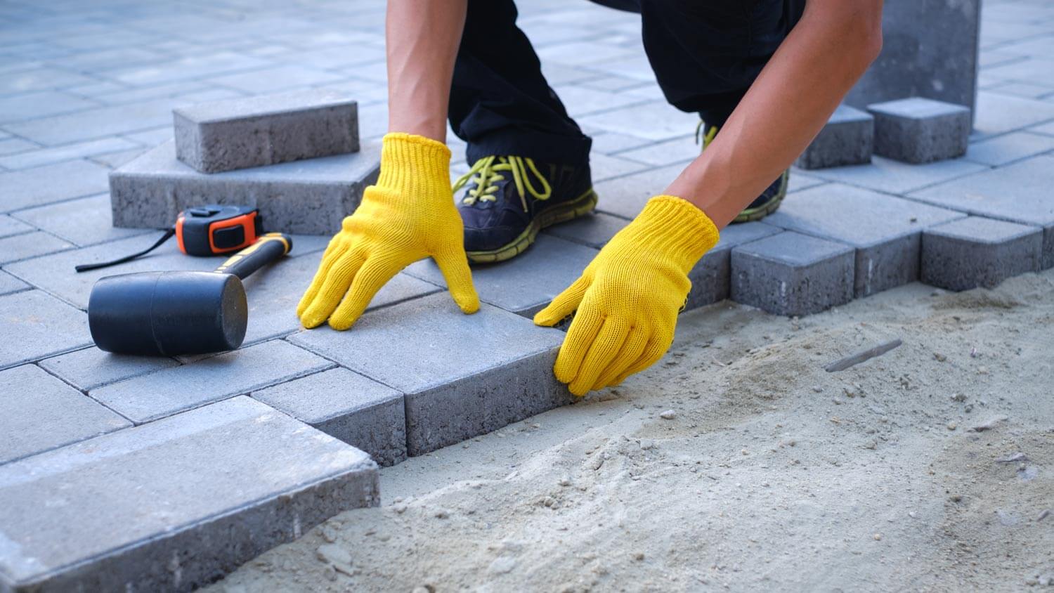 A worker laying concrete pavers