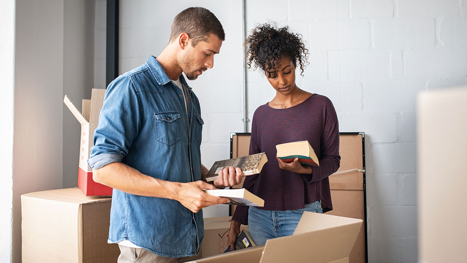 Couple packing books in cardboard boxes