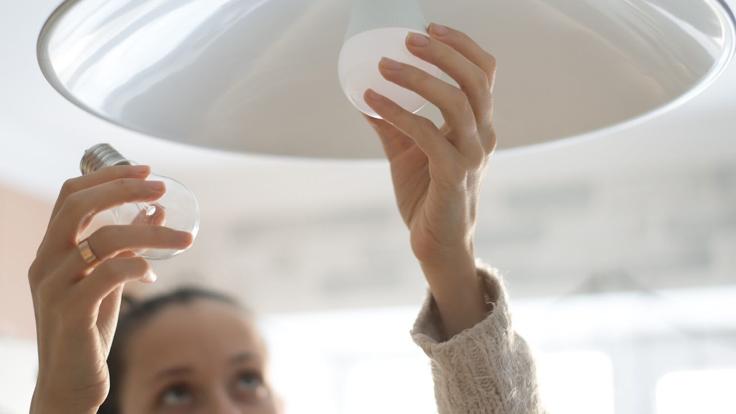 A woman switching an incandescent bulb to a led one