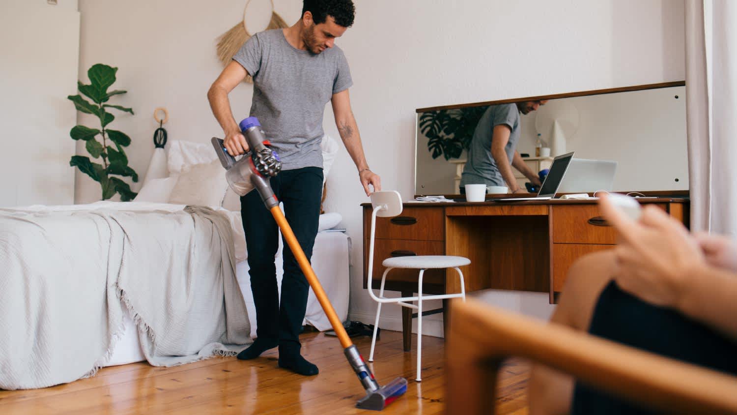 A man cleaning bedroom with vacuum cleaner