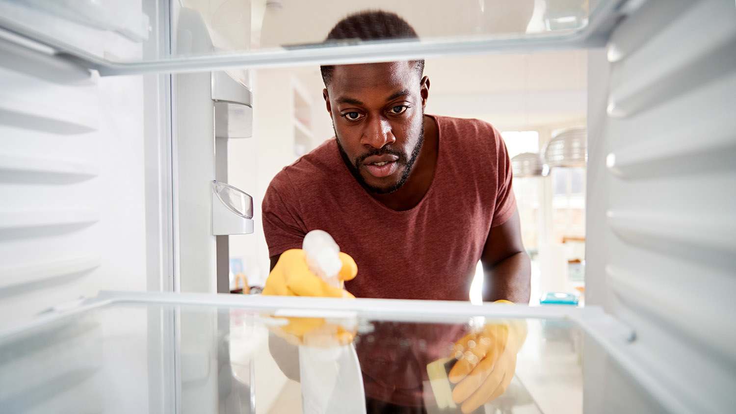 man cleaning inside of fridge