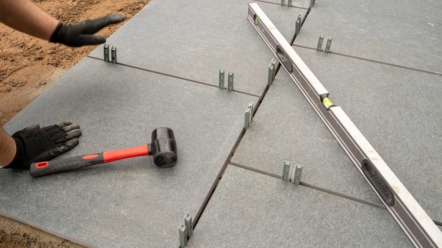Worker laying porcelain pavers in the backyard