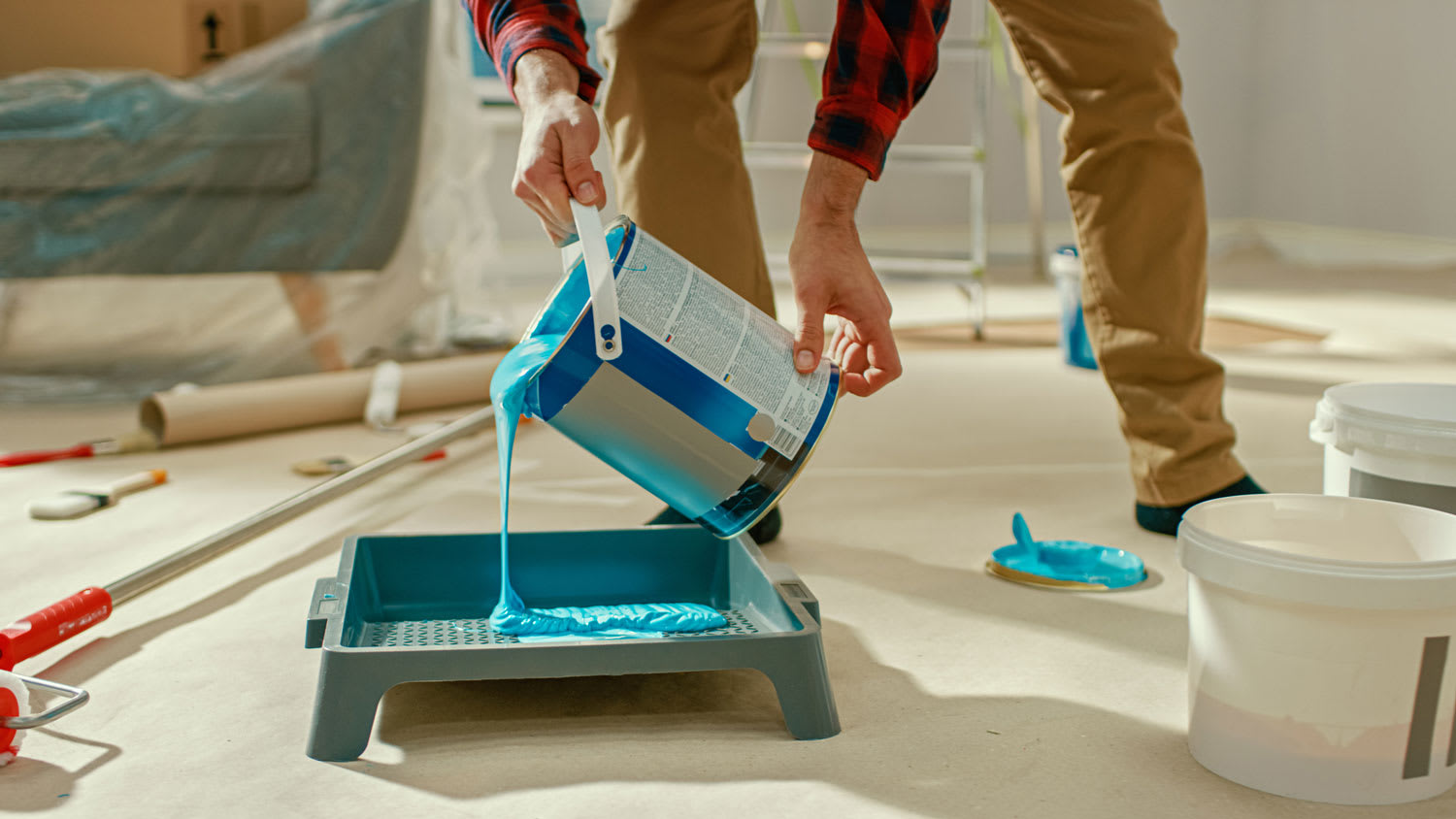 A man pouring paint from a can to a tray