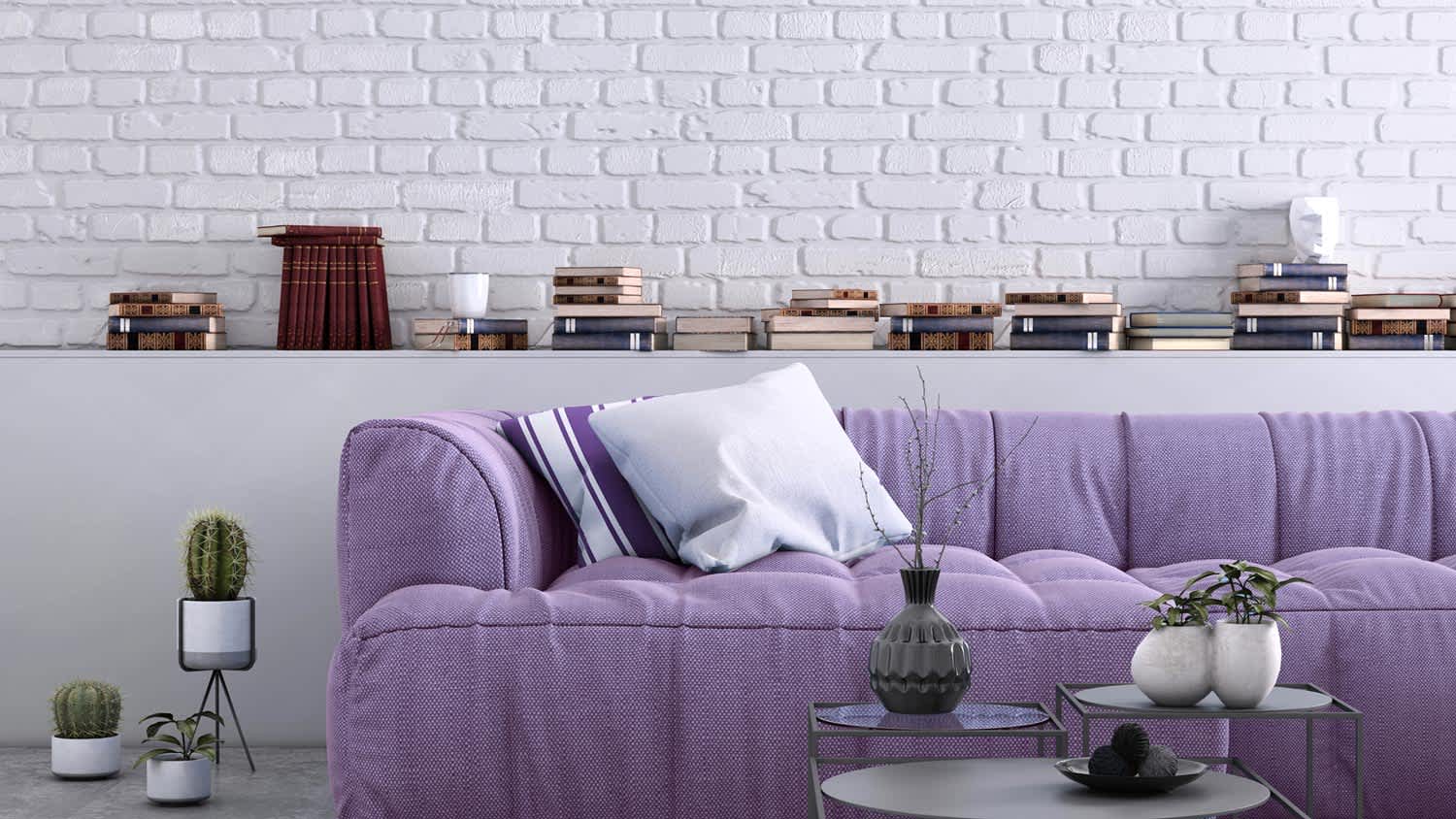 A purple sofa in a living room with white painted exposed brick wall