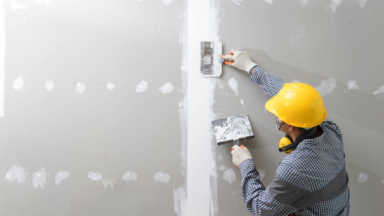 A worker plastering the wall indoors