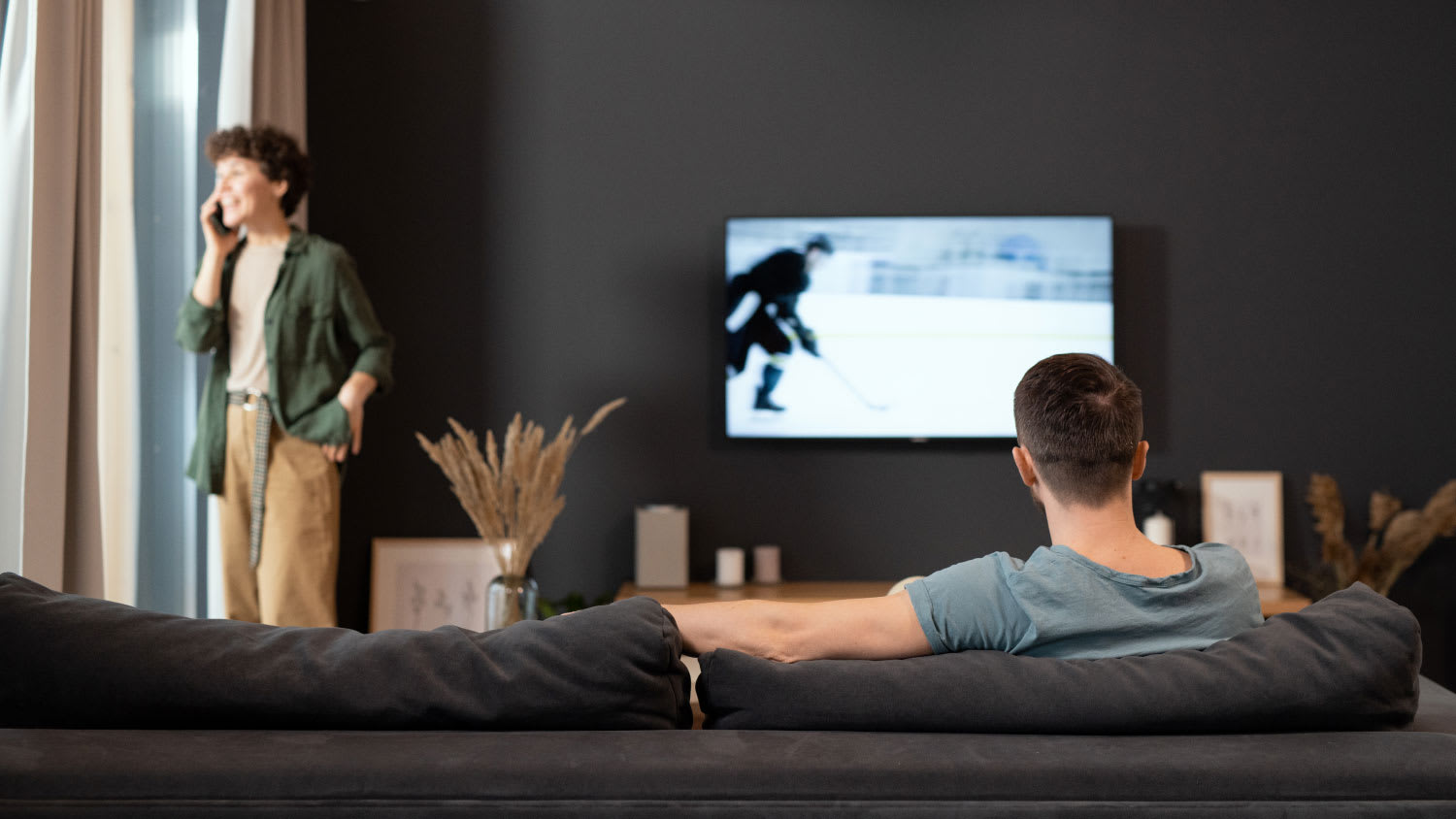 man sitting on couch watching hockey on TV