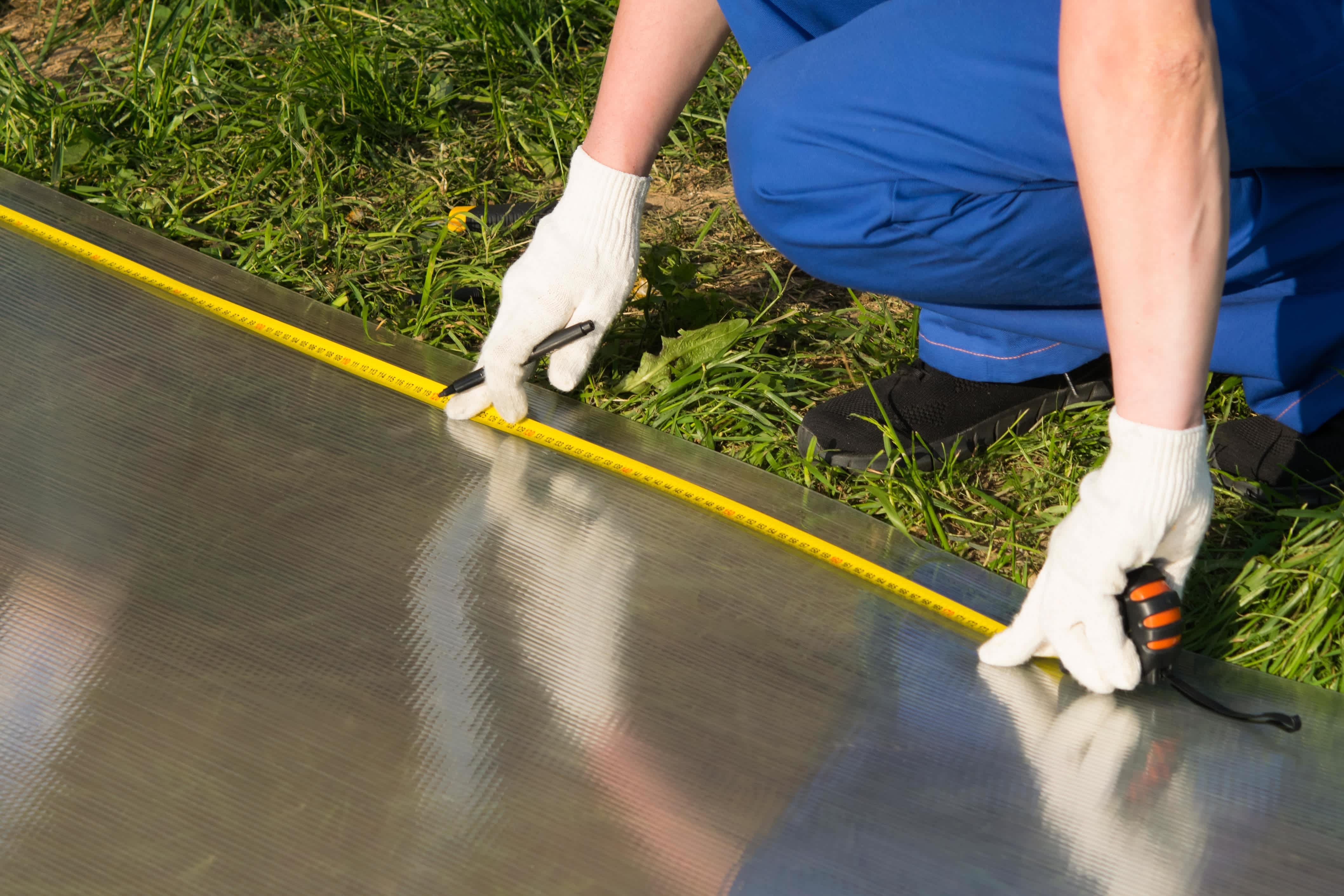 A construction worker using a measuring tape on a polycarbonate sheet