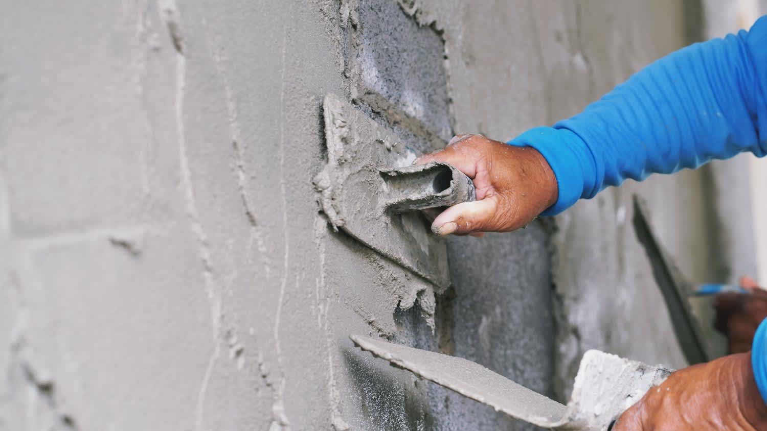 A worker plastering cement on wall