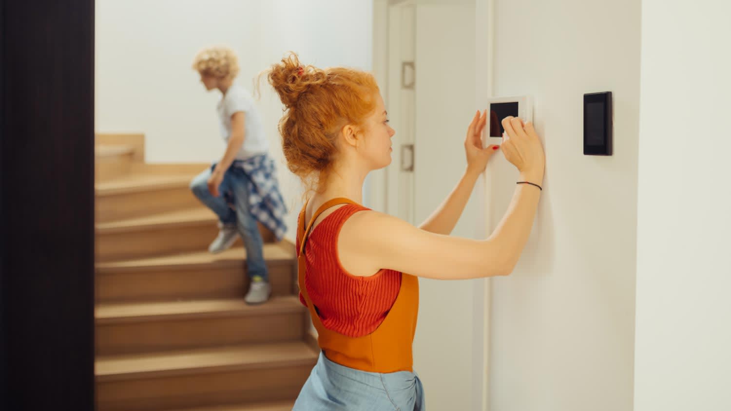 young woman setting alarm on wall