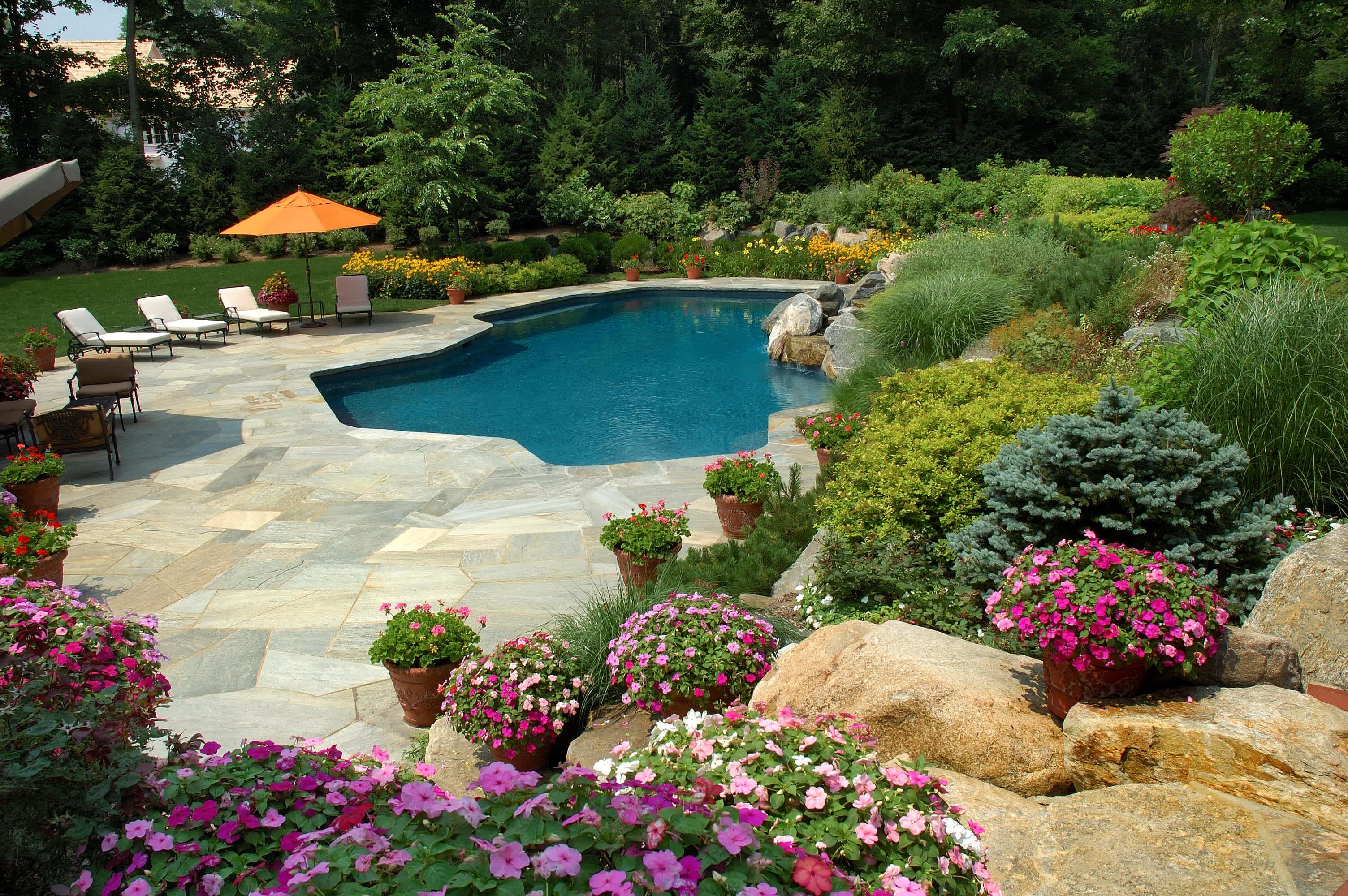 A backyard in-ground pool surrounded by a stone tile patio