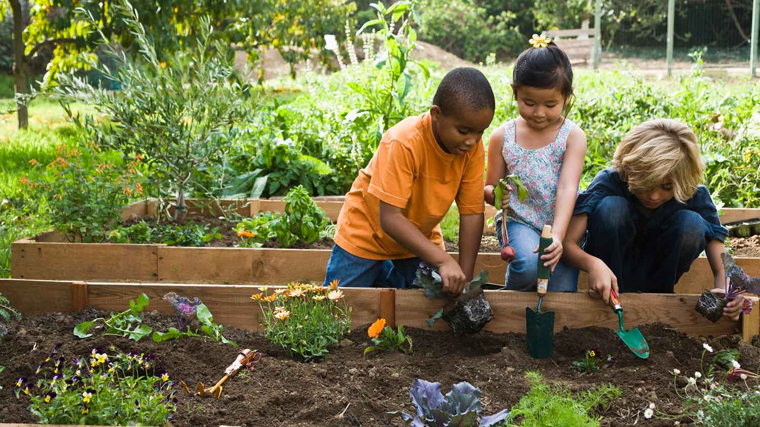 Children using gardening tools to plant flowers