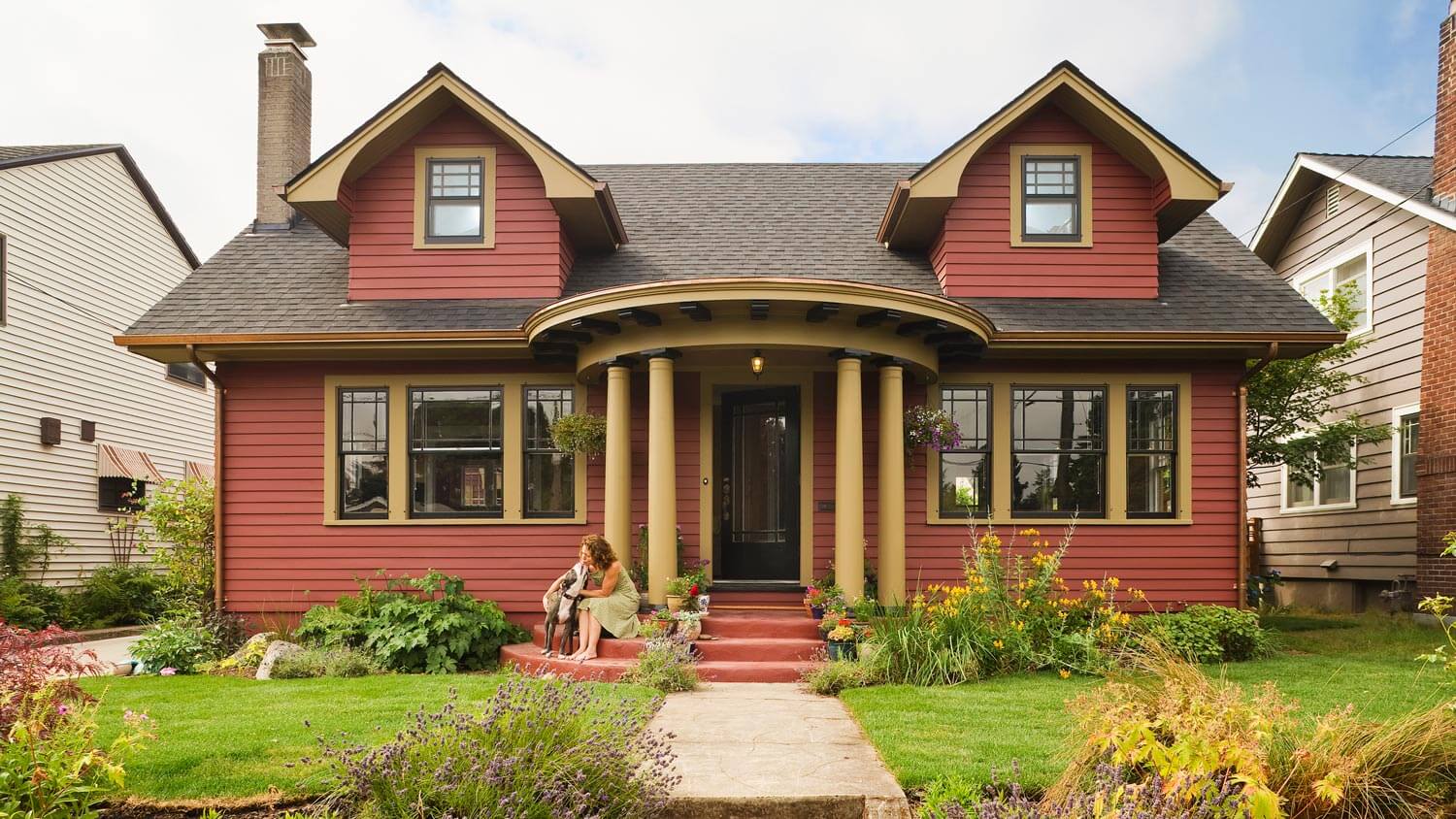 The exterior of a house with a woman hugging her dog