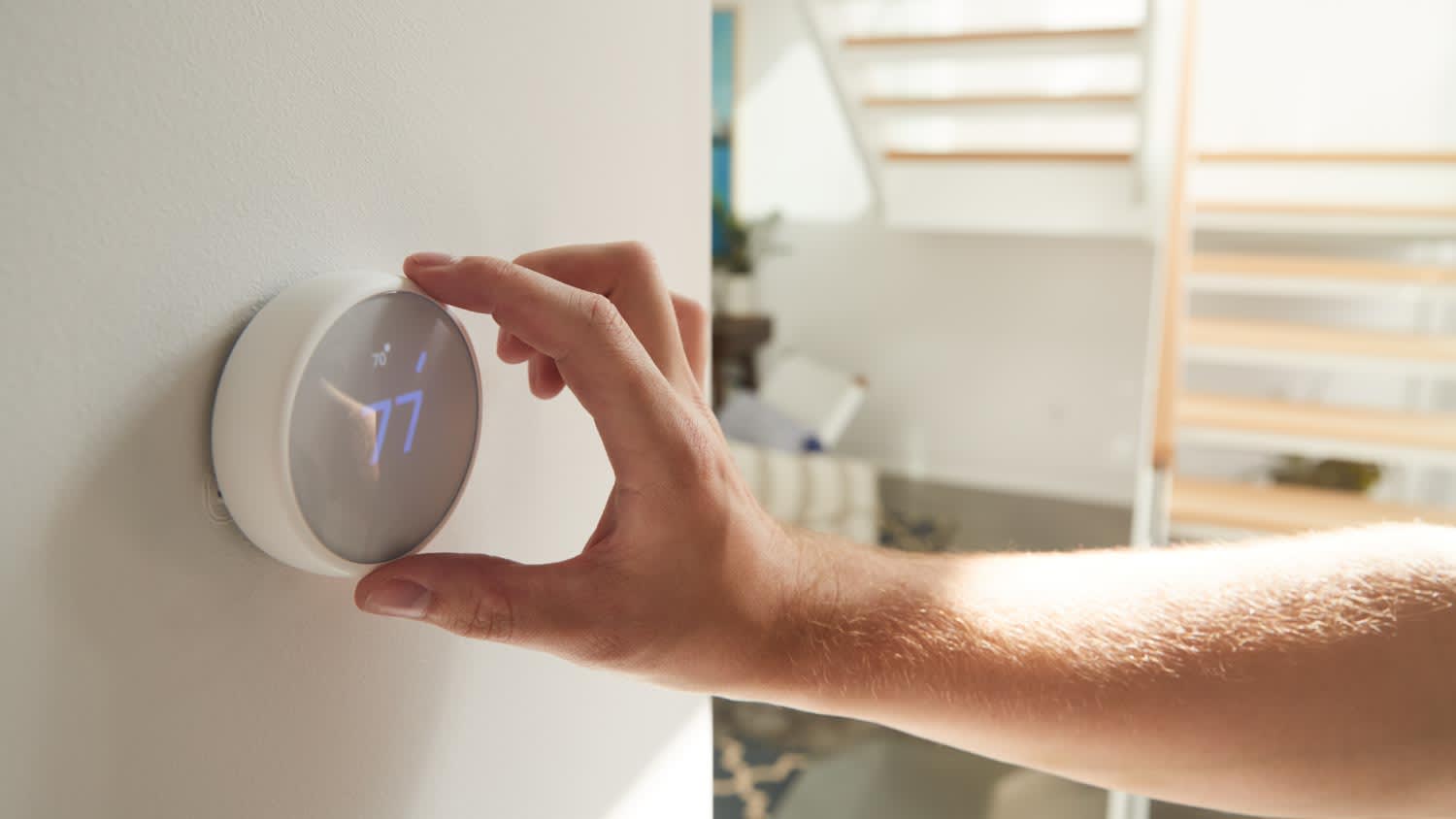 A close-up of man adjusting digital central heating thermostat