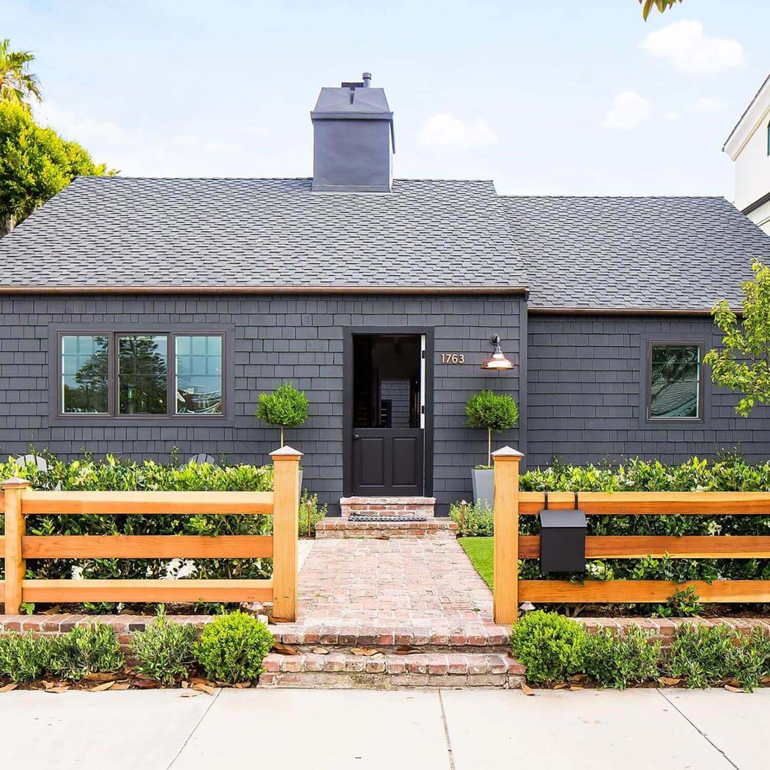 A black facade house with privacy hedges