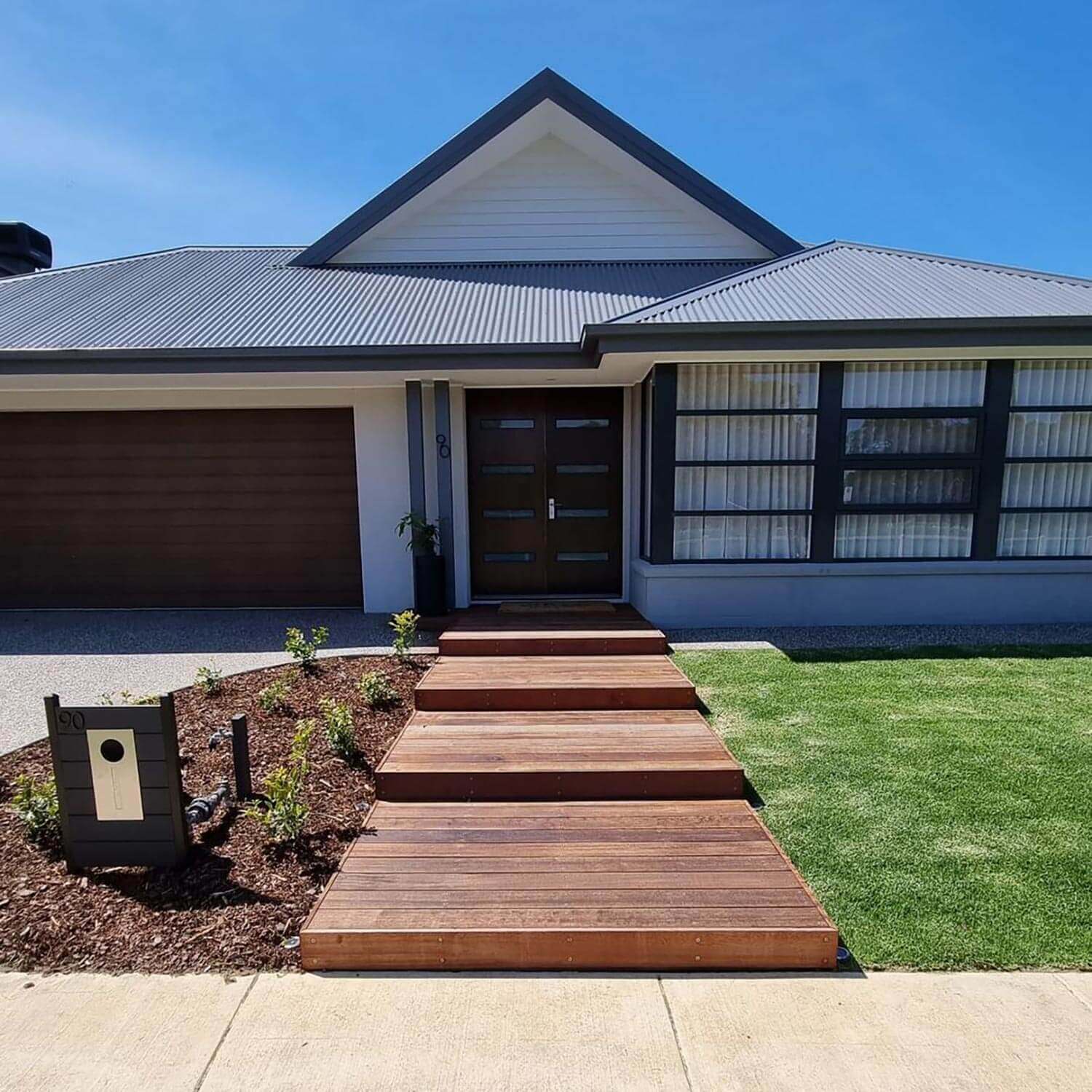 A front yard of a house with timber decking steps