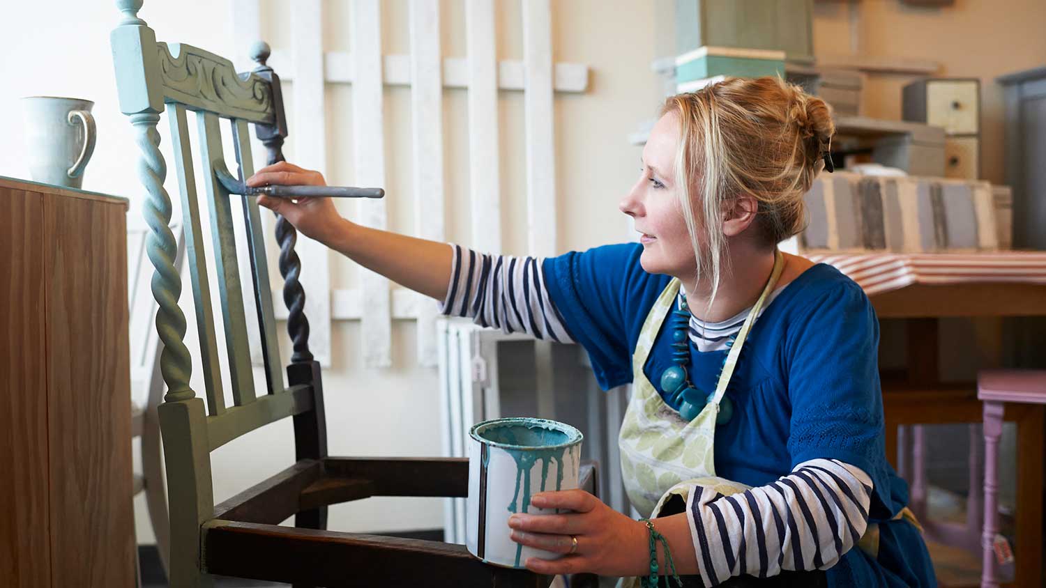 Woman painting wooden vintage chair with a brush