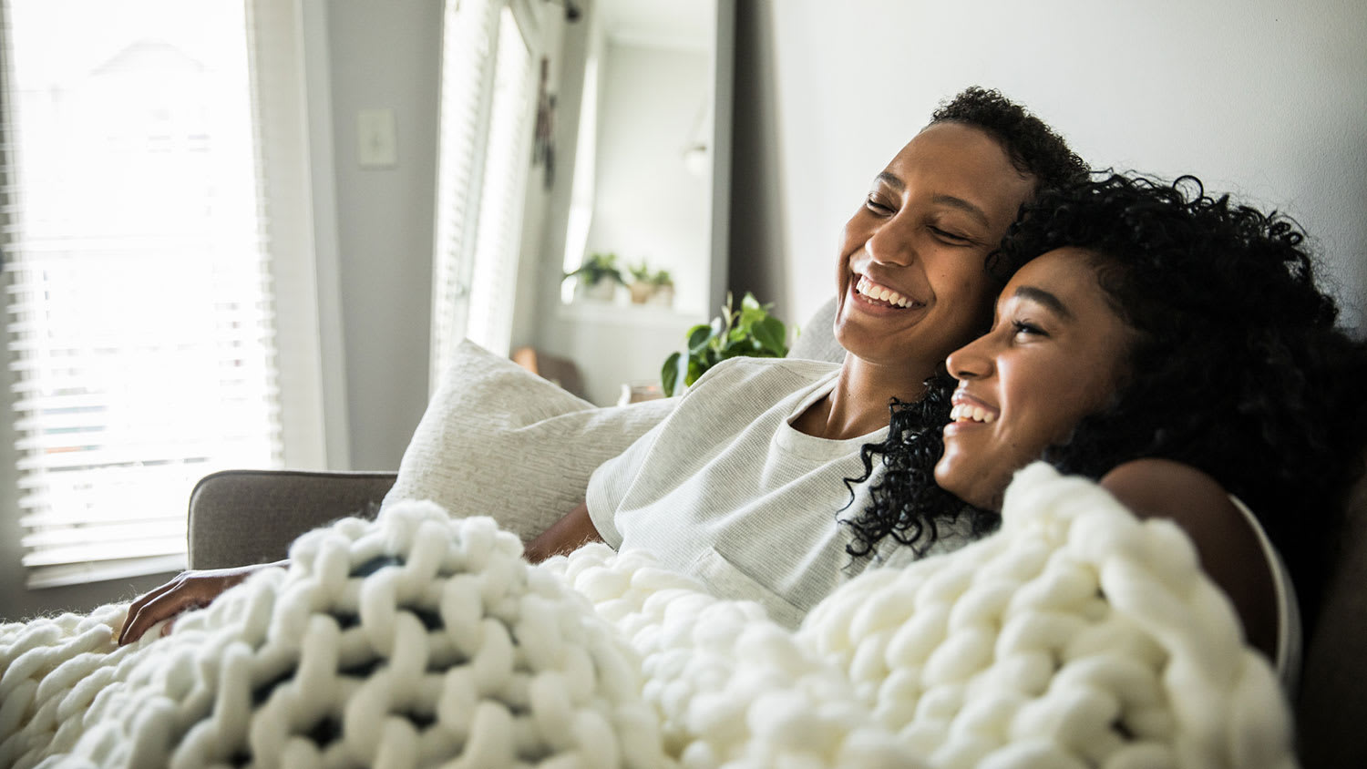 Couple snuggling under blanket at home