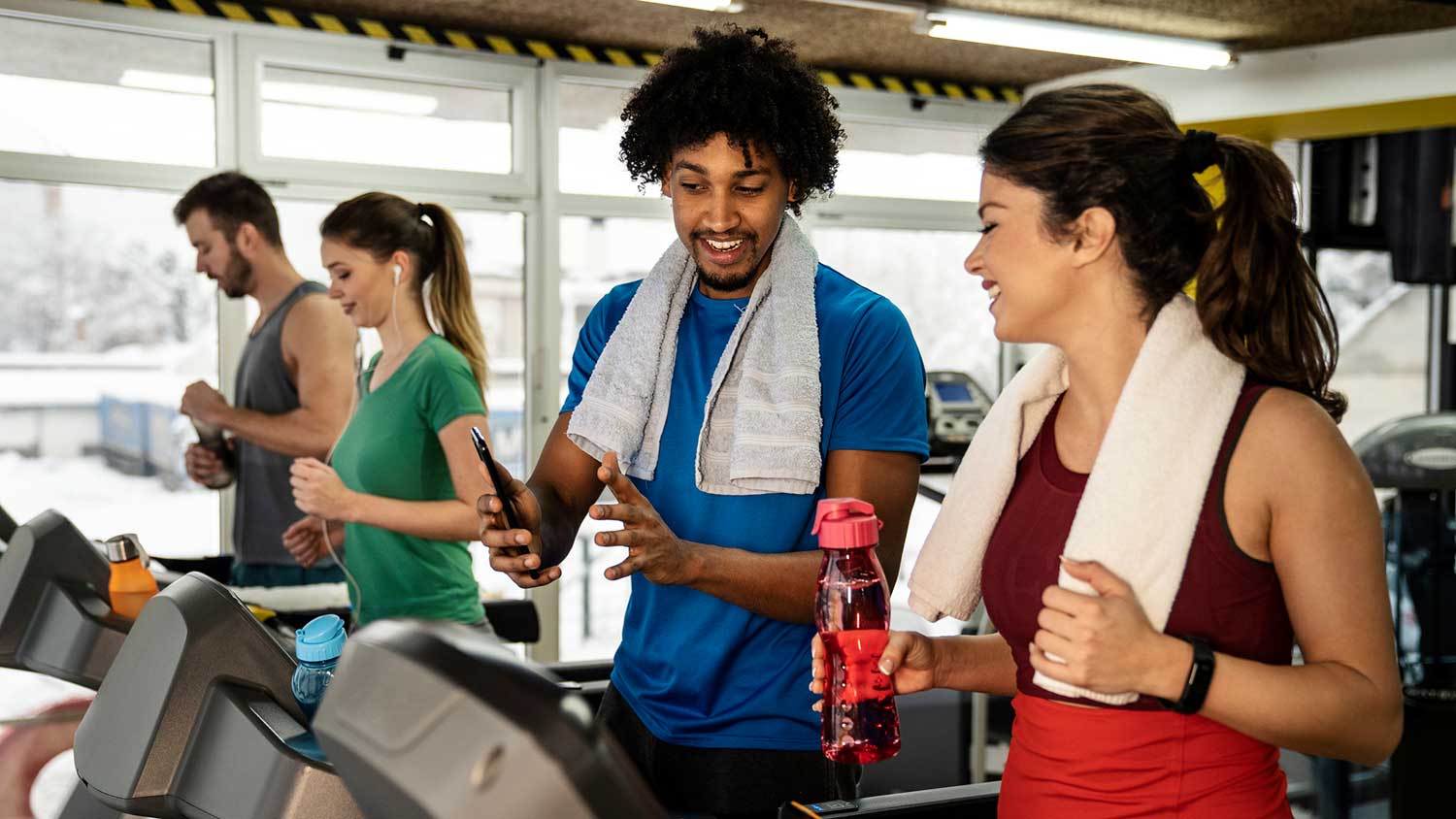 Friends chatting and using treadmills at the gym