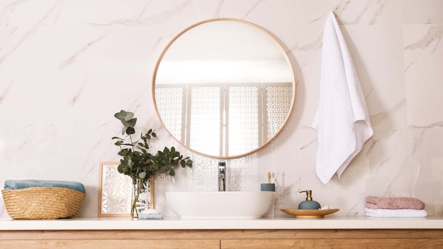 A bathroom vanity with a round mirror