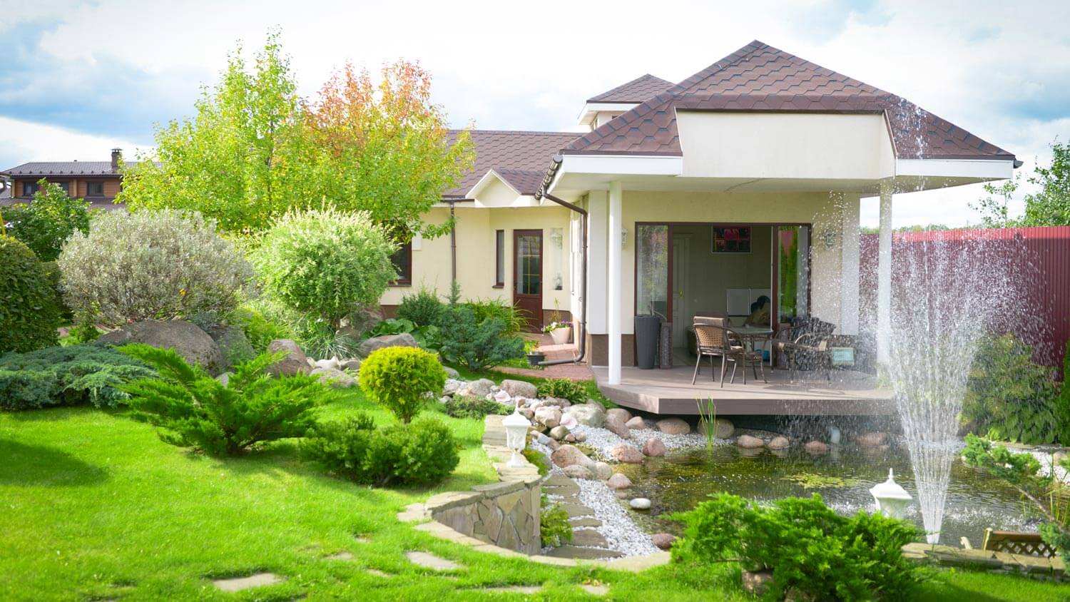 A landscaped garden with rocks and fountain in front of the house