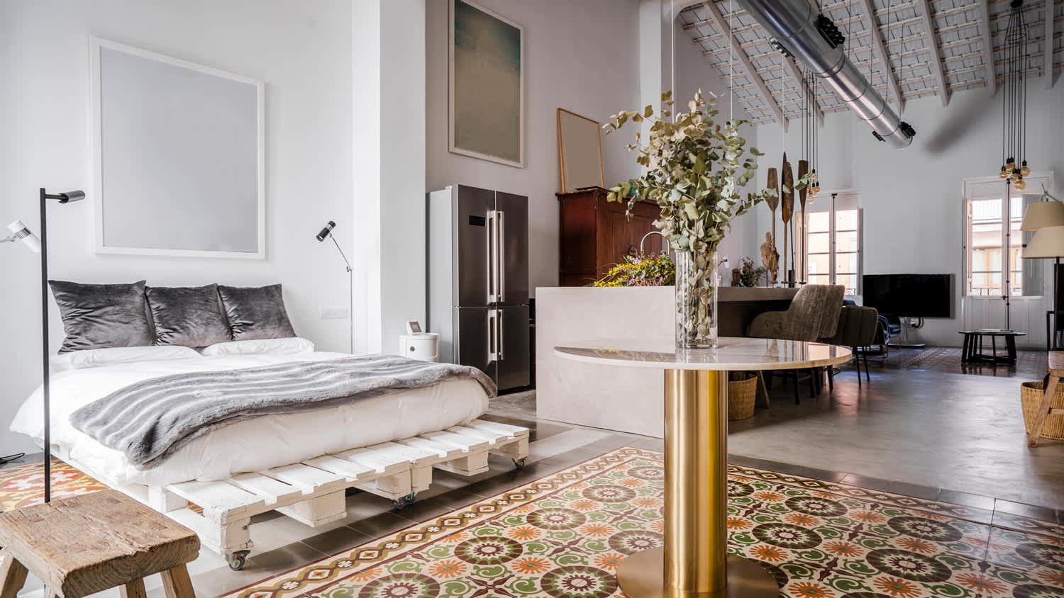 An open plan loft with a bed and industrial vents