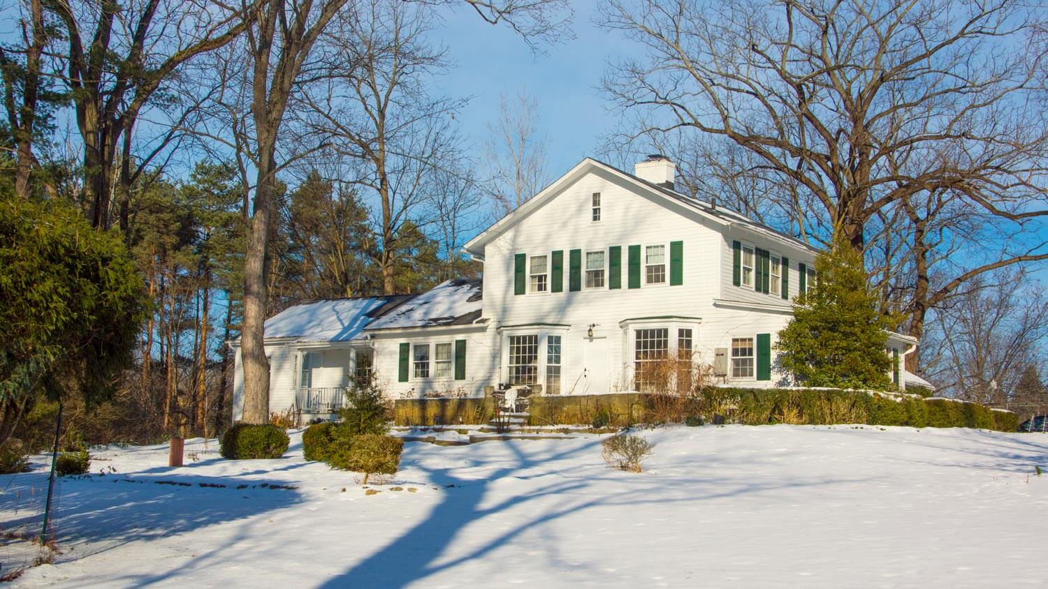 A white historic house covered in snow