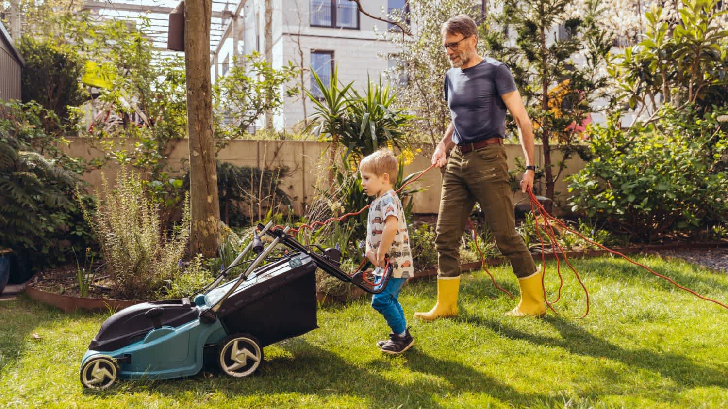 Father and son mowing the lawn together
