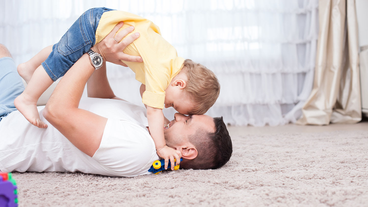 Dad playing with son on the carpet