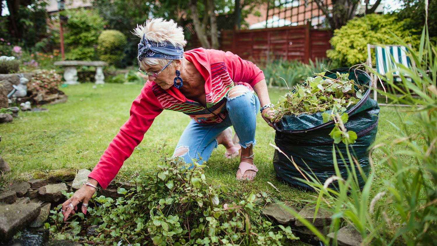 Woman gathering garden waste in a compost bag