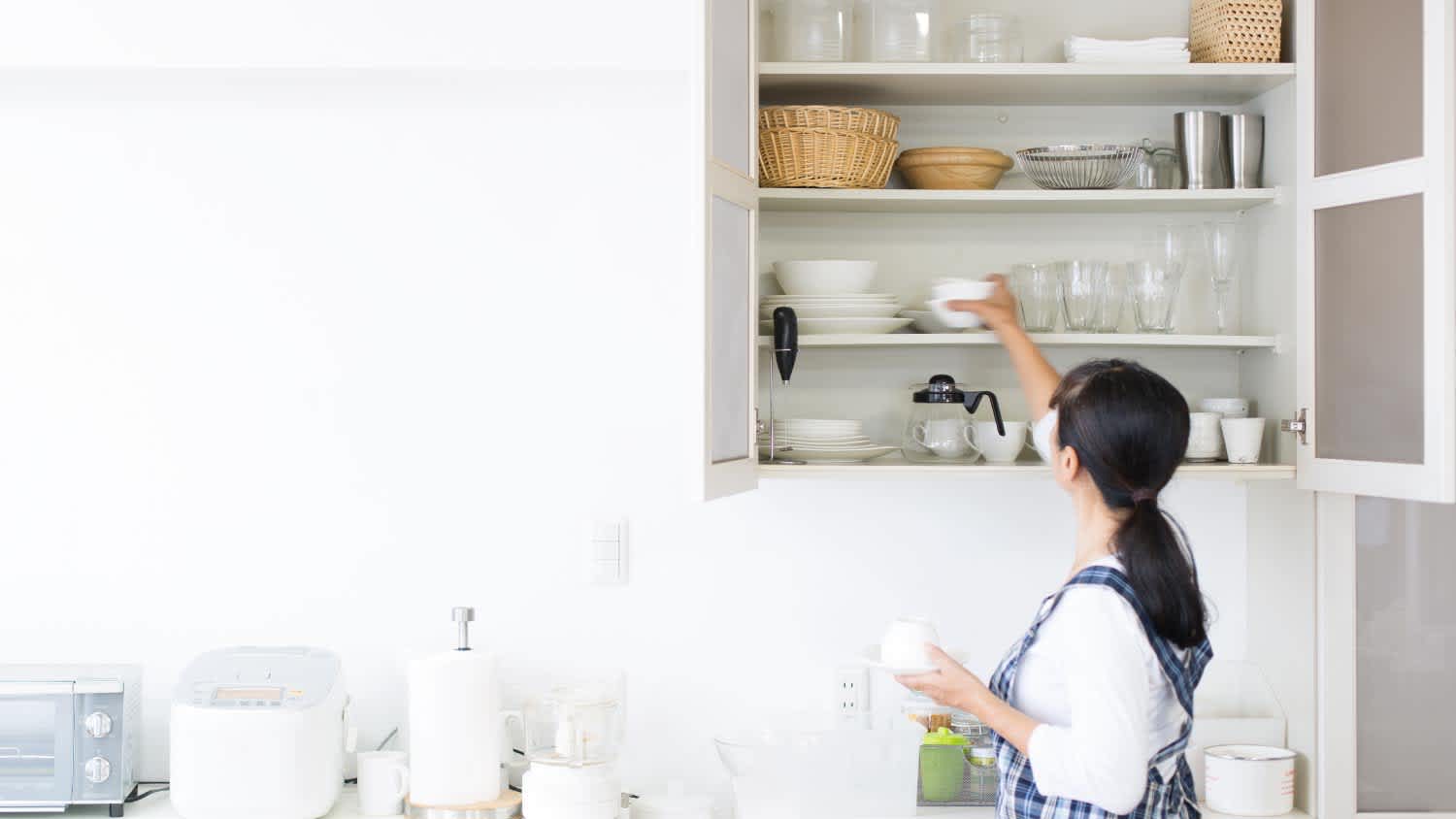 A woman cleaning her kitchen cabinets