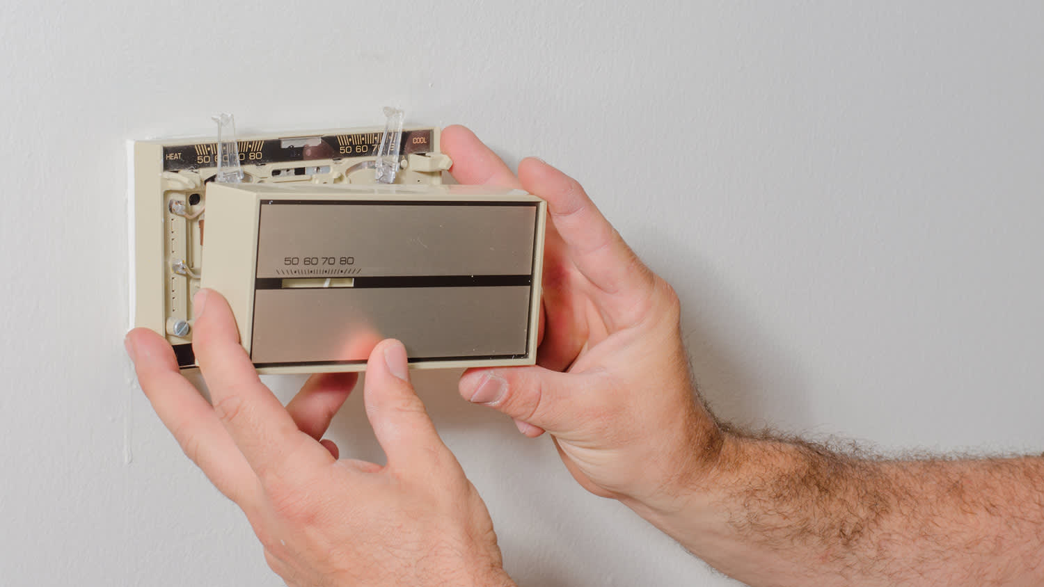 Hands removing a mercury thermostat cover