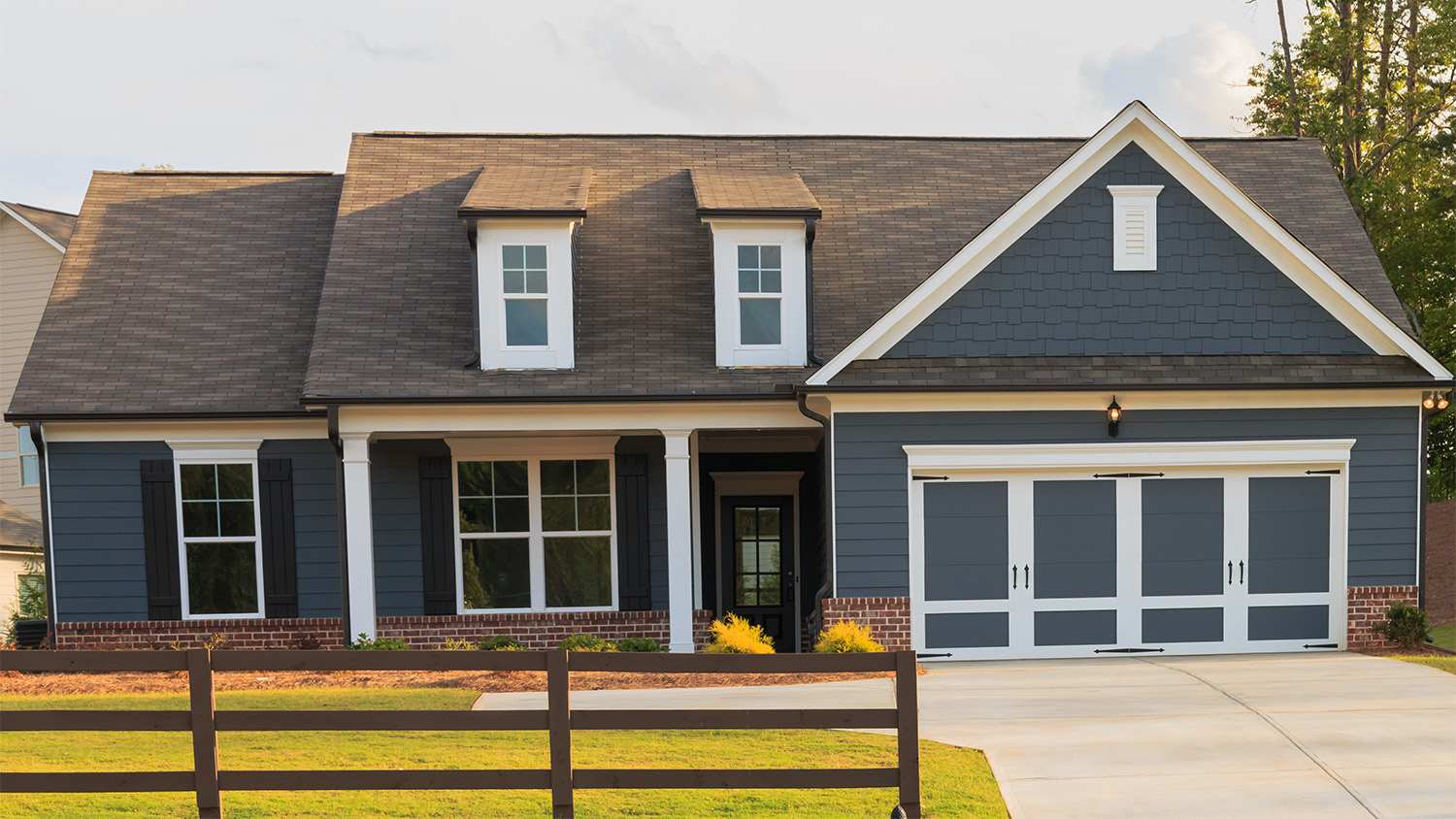 A dark blue ranch home with dark grey asphalt shingles