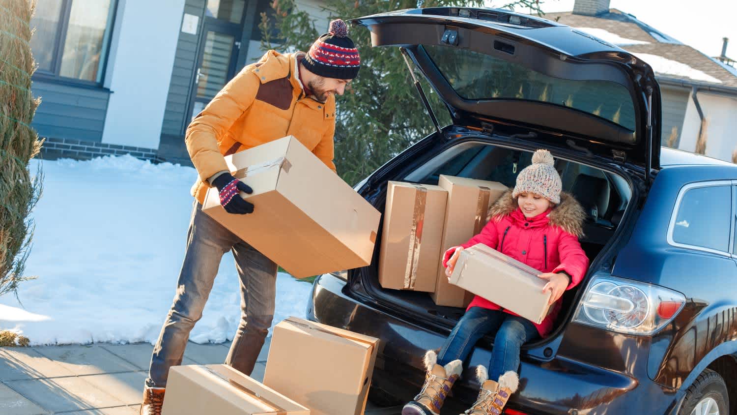 A father with his daughter loading a car with moving boxes