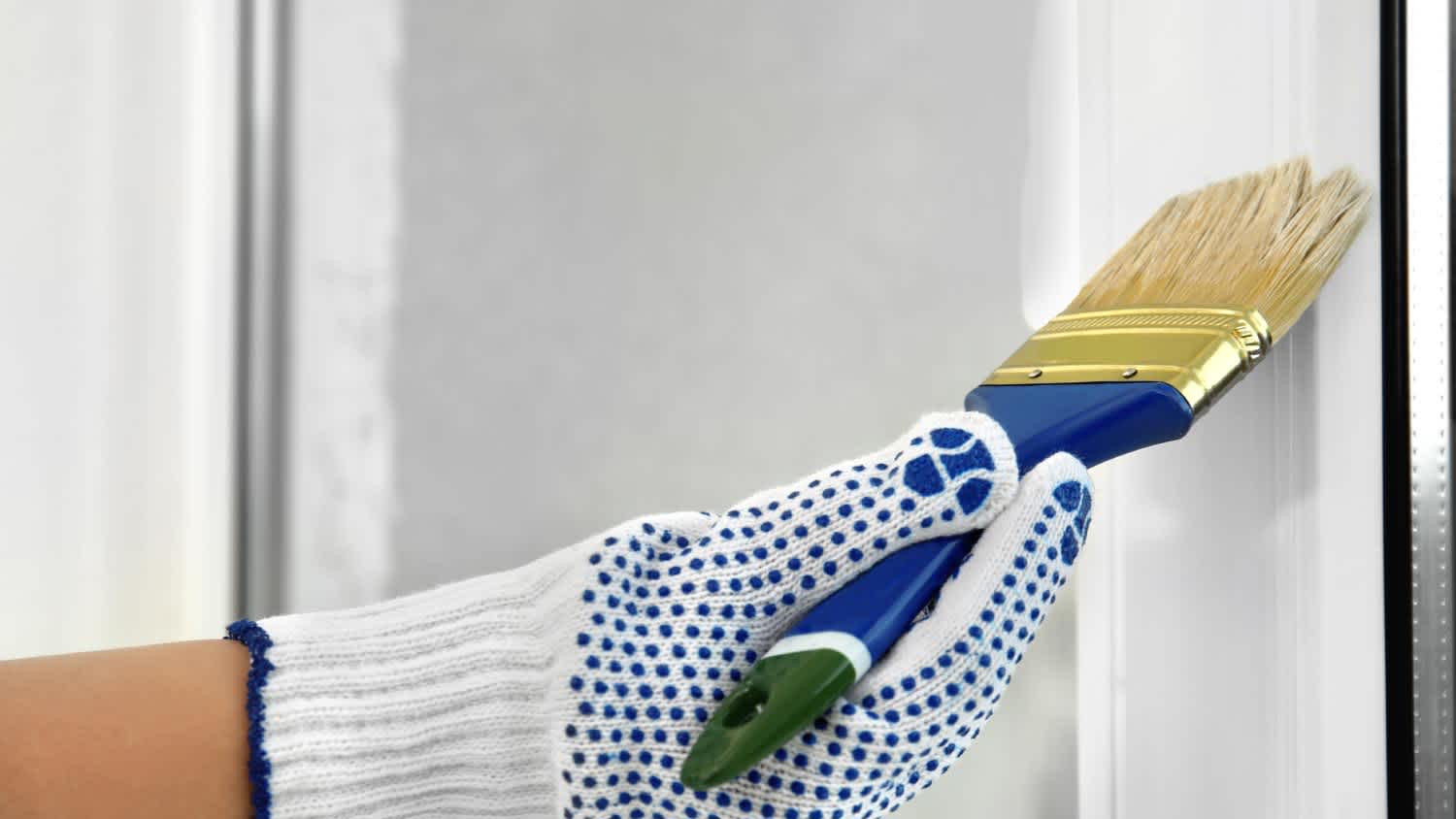 A woman painting window frame at home