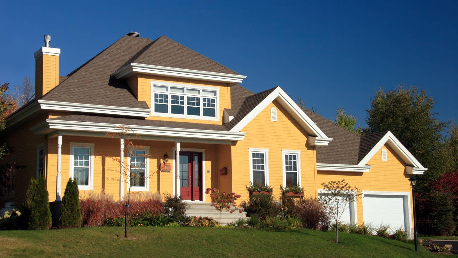 The exterior of a yellow house with a nice roof