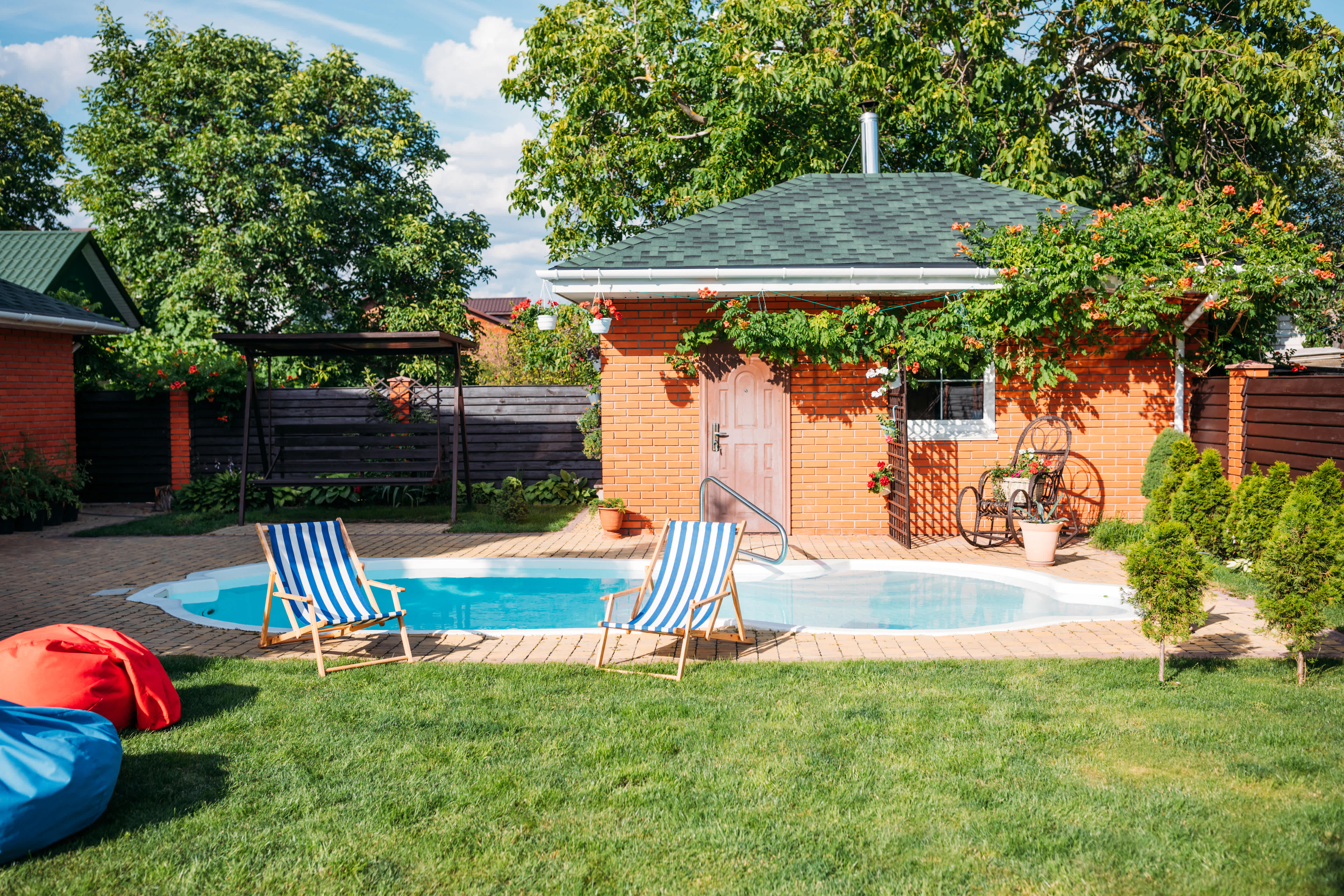 An inground pool with a large brick pool house