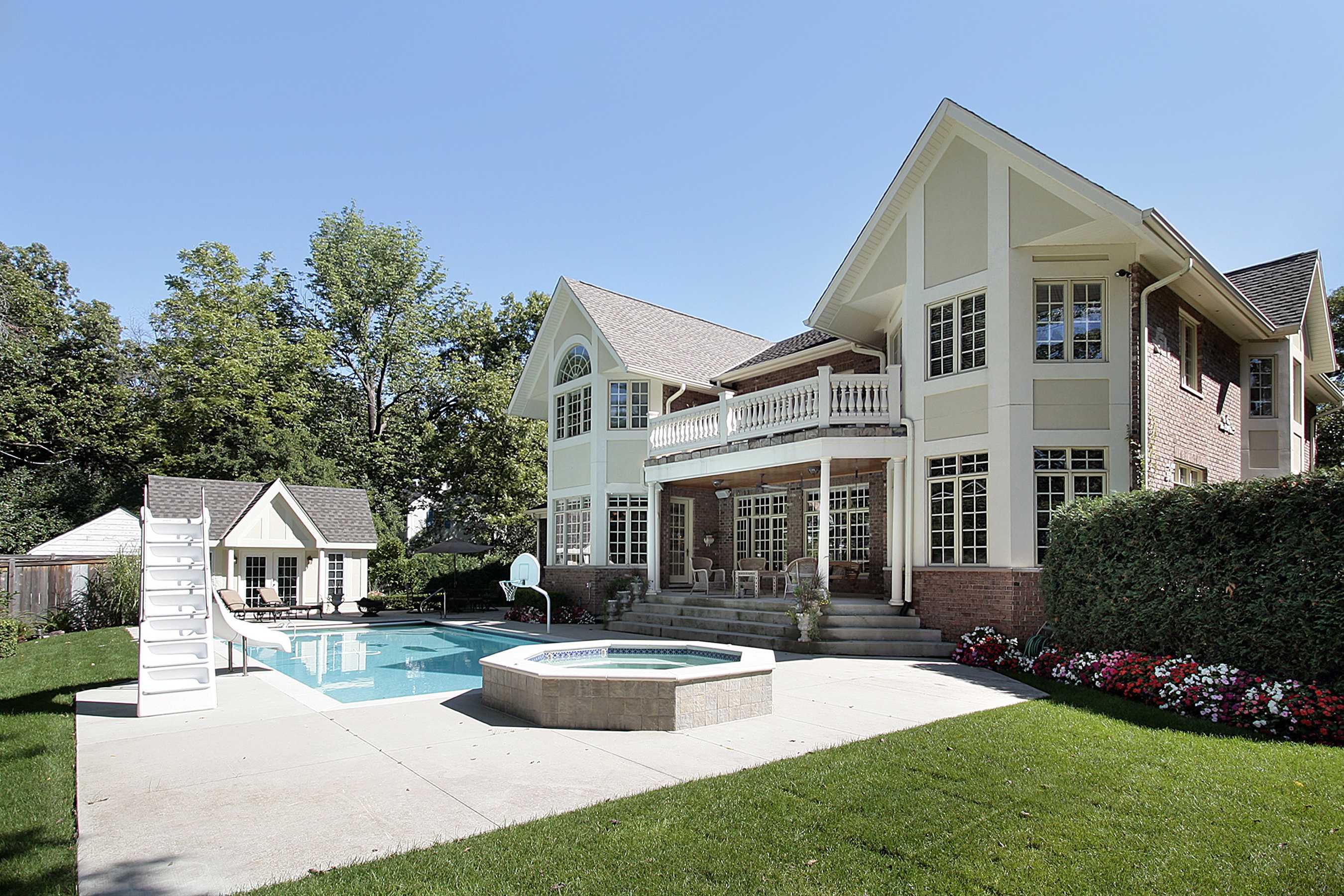 A large luxury home with an inground pool and large pool house