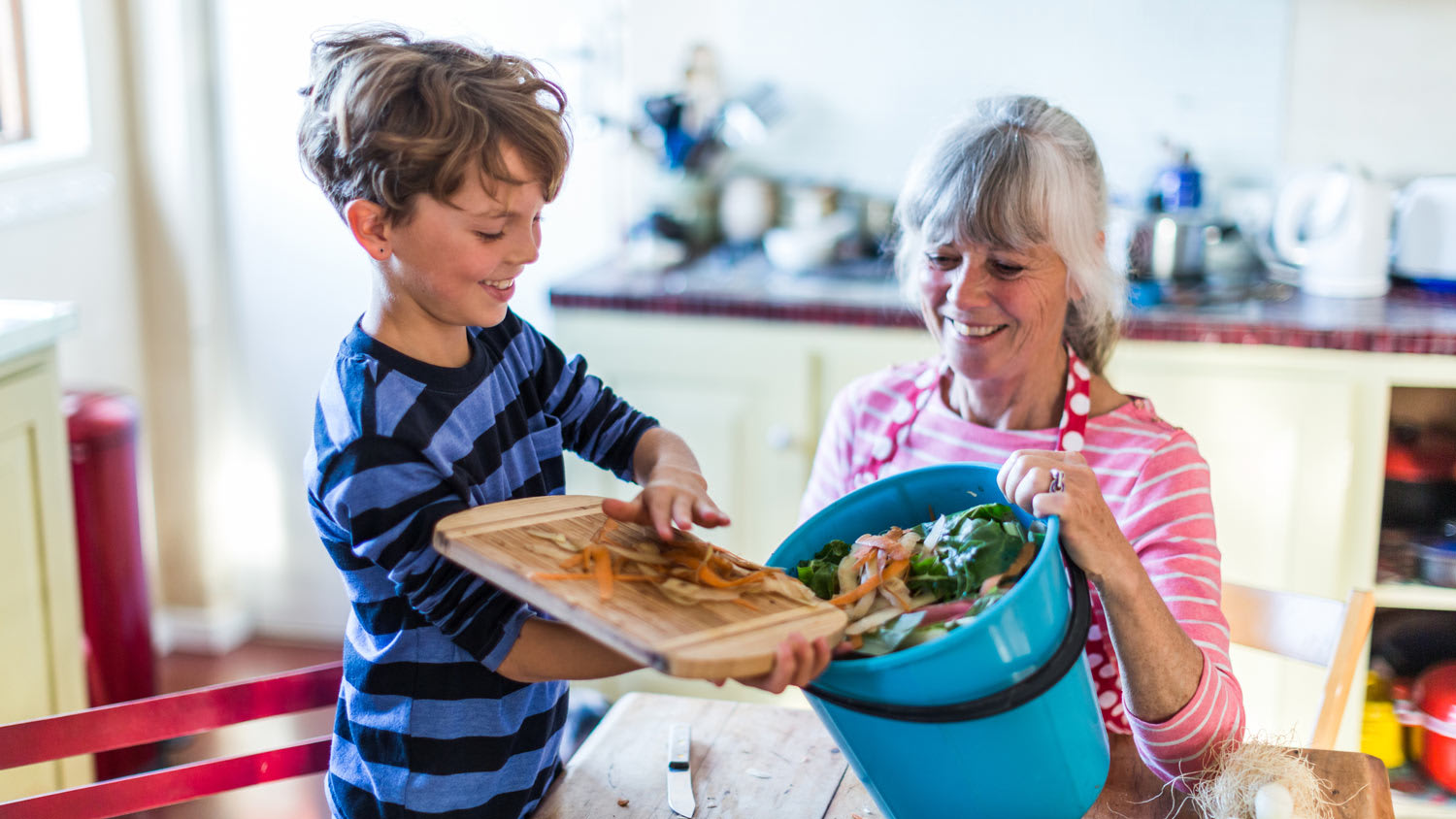 A grandson helping his grandmother with kitchen waste for composting