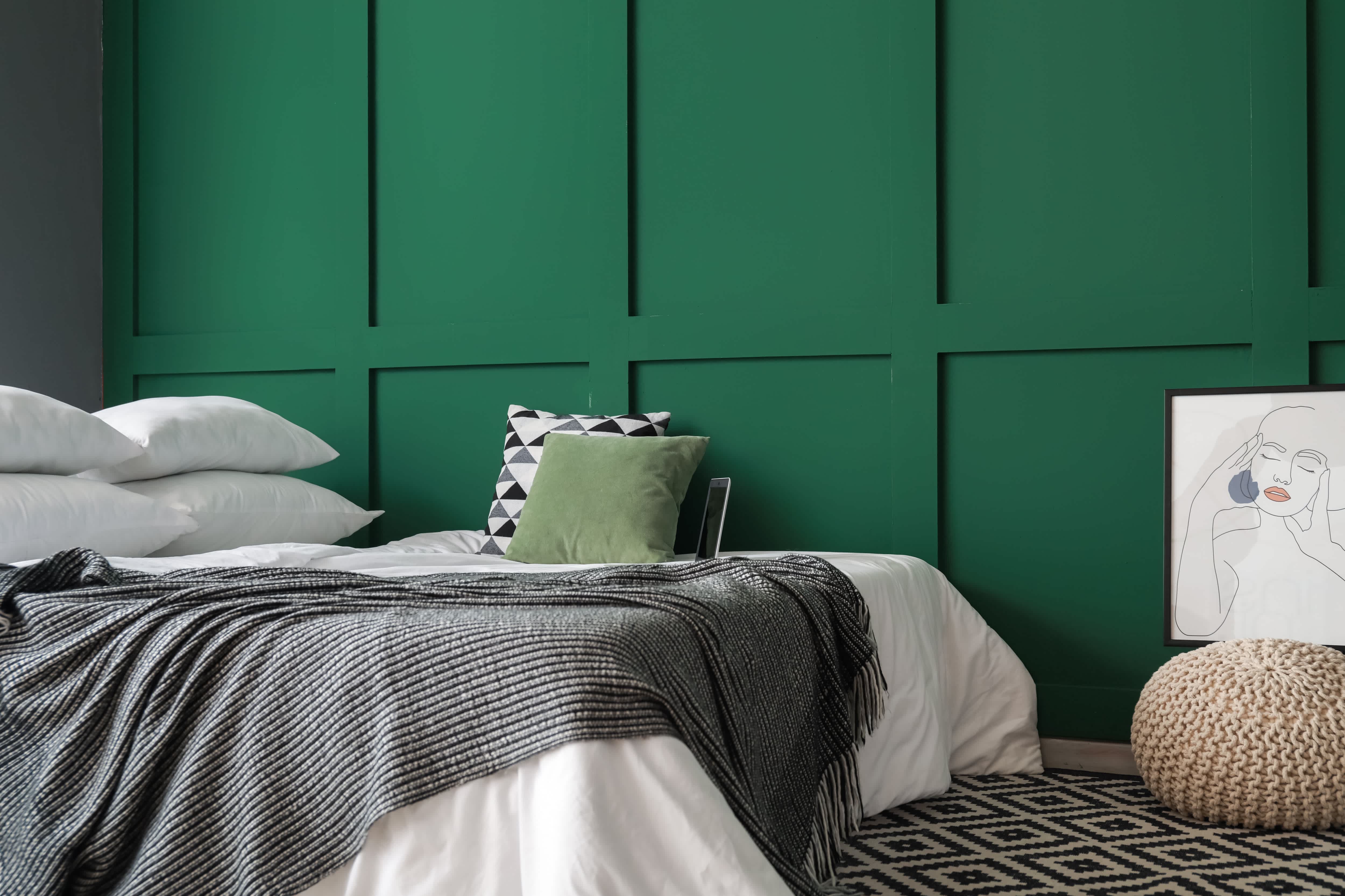 Comfy bed pushed up against kelly green colored board and batten wall