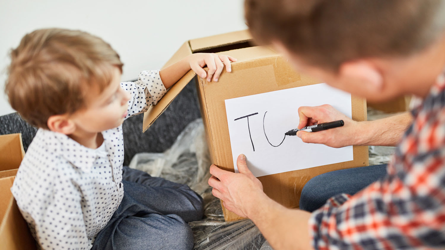 A father and his son labelling moving boxes