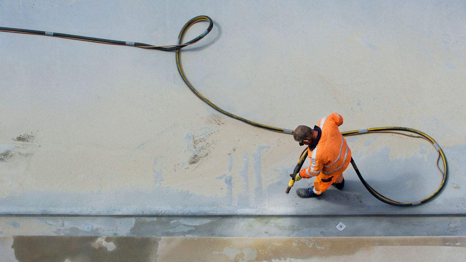 Worker wearing protective uniform sandblasting floor