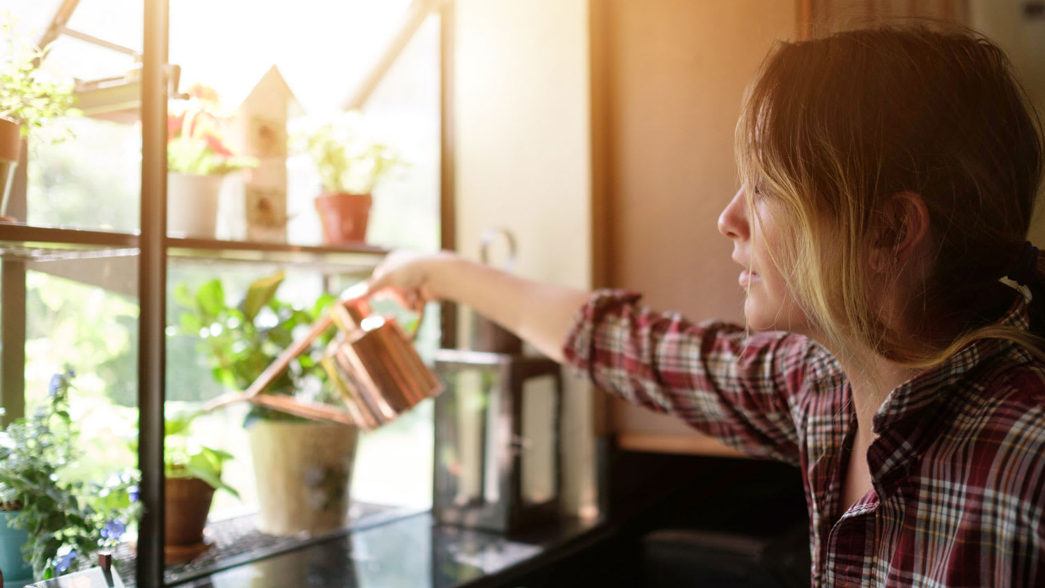 A woman watering plants placed on a garden window