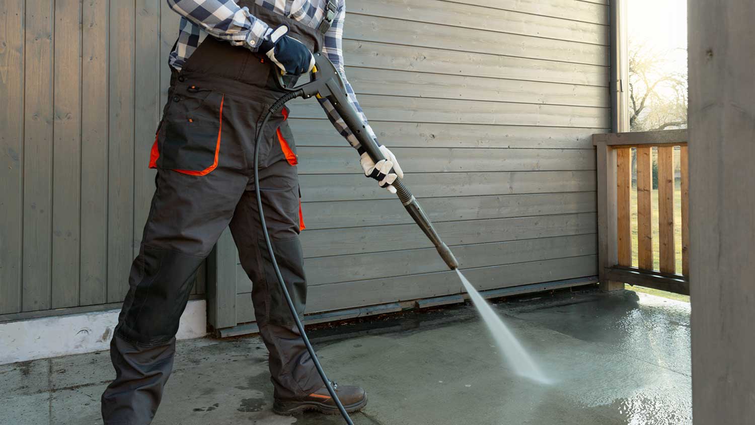 Worker power washing concrete terrace