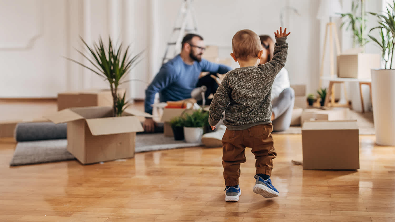 toddler walking toward parents in new home