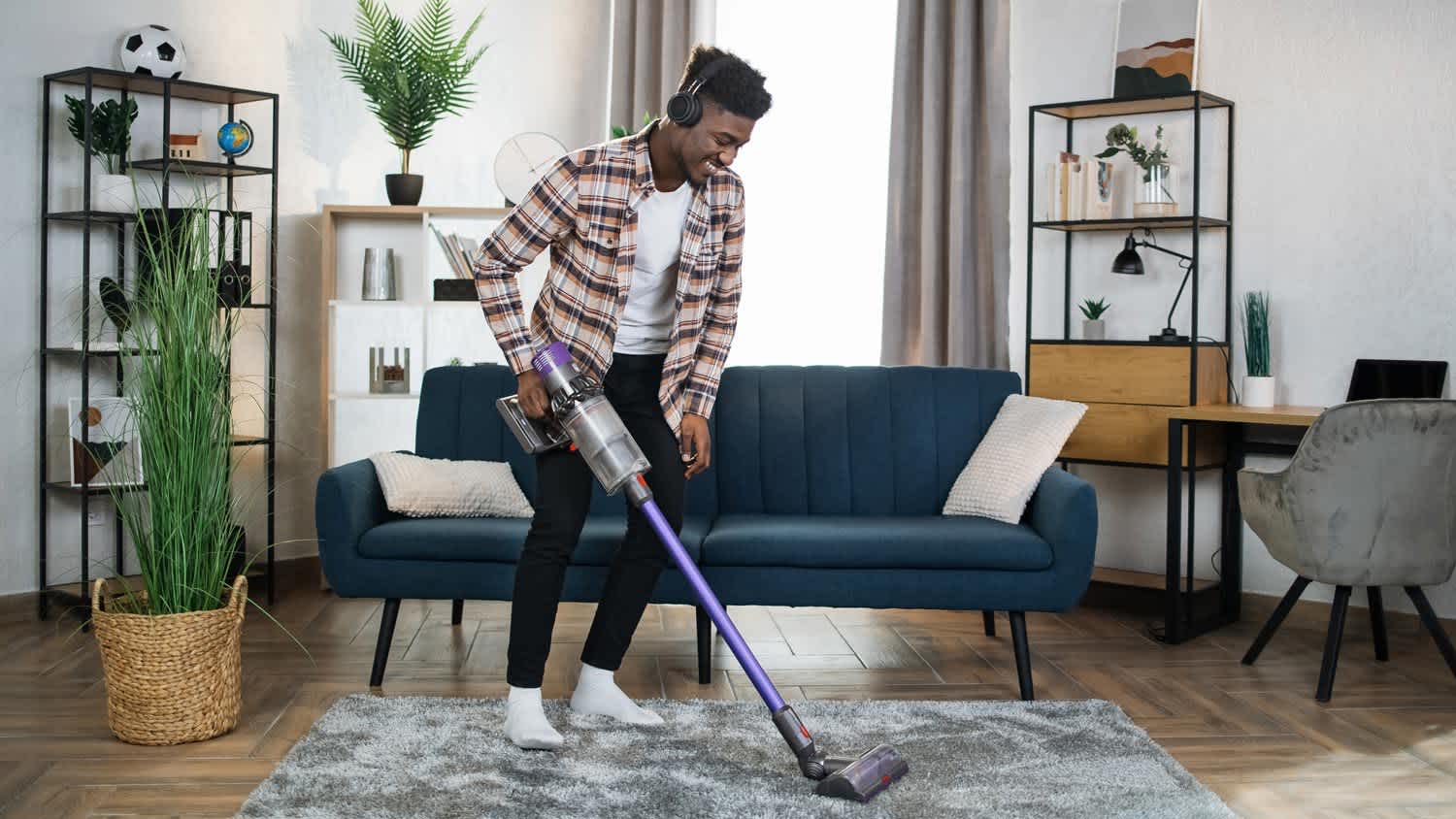 A young man in headphones vacuuming his house