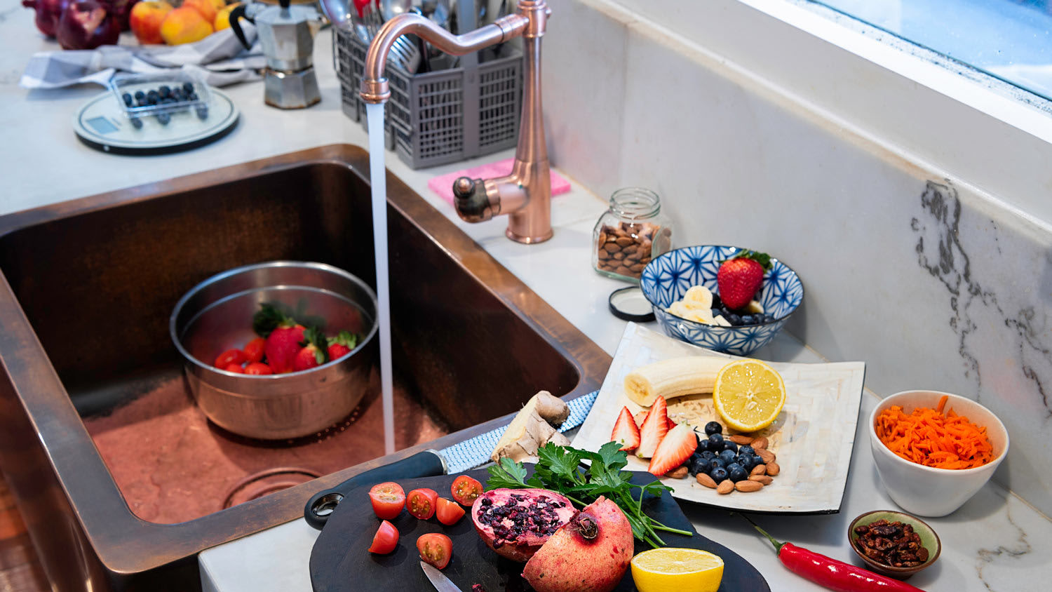Fruits and vegetables getting washed in a copper kitchen sink