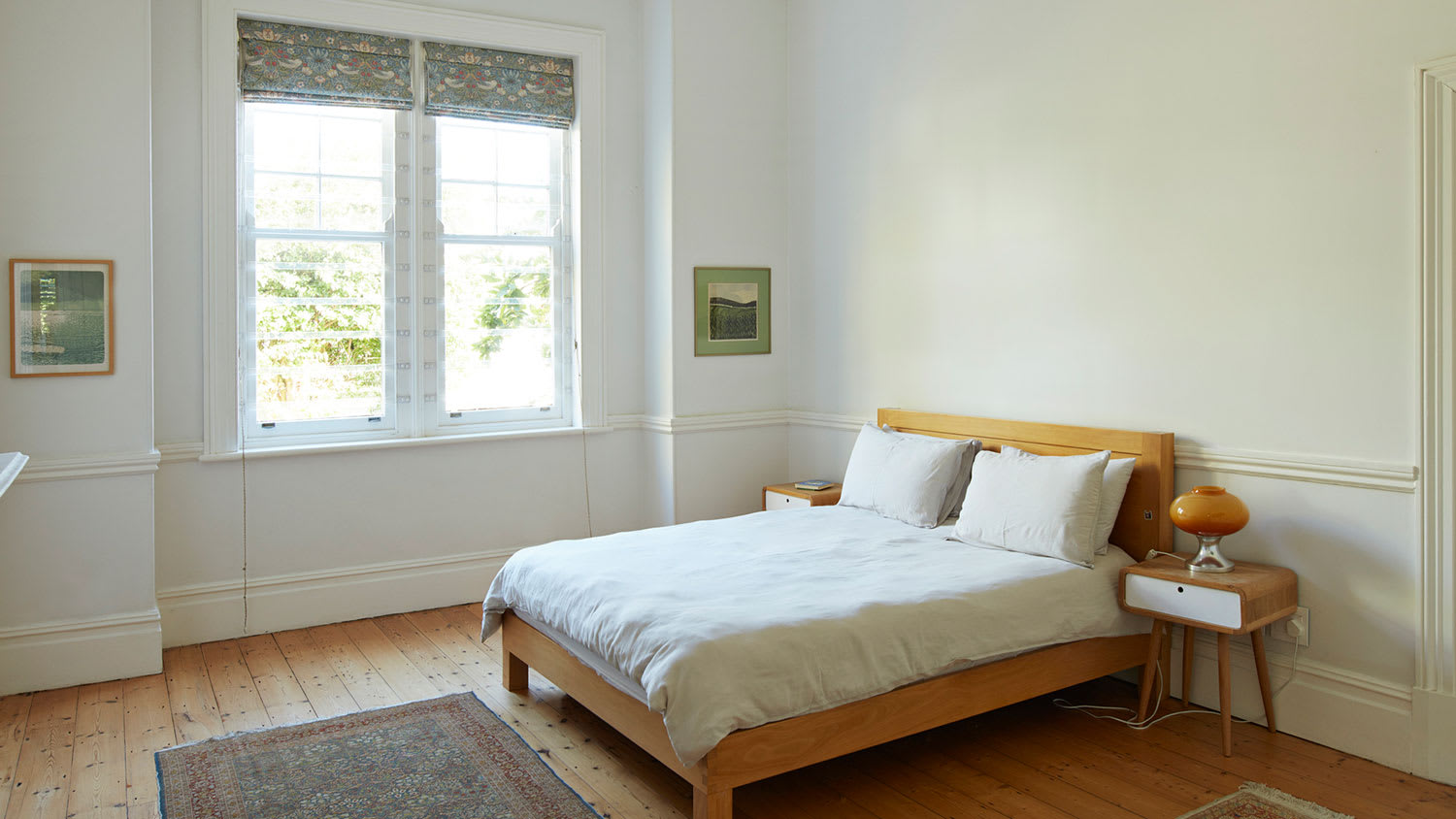 White bedroom with wooden bed by the window