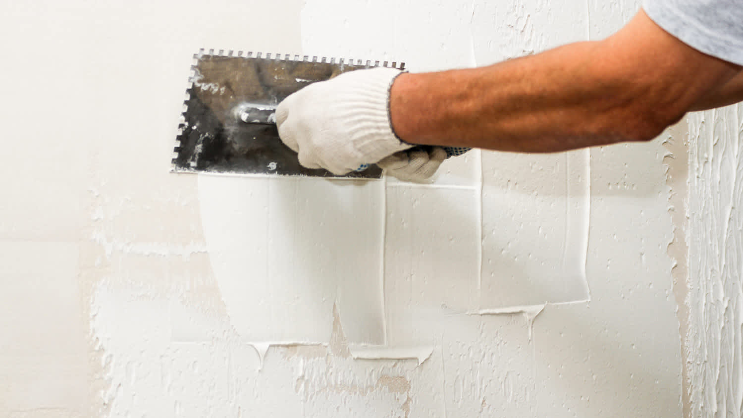 A professional applying plaster on a wall with a comb